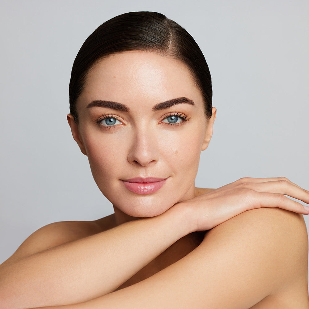 Eine junge Frau trägt die jane iredale Foundation Skintuition und lächelt in die Kamera