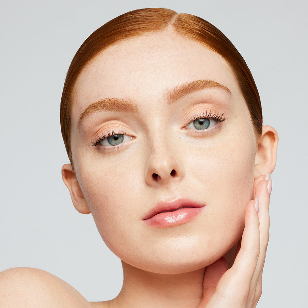Eine junge Frau trägt die jane iredale Foundation Skintuition und lächelt in die Kamera