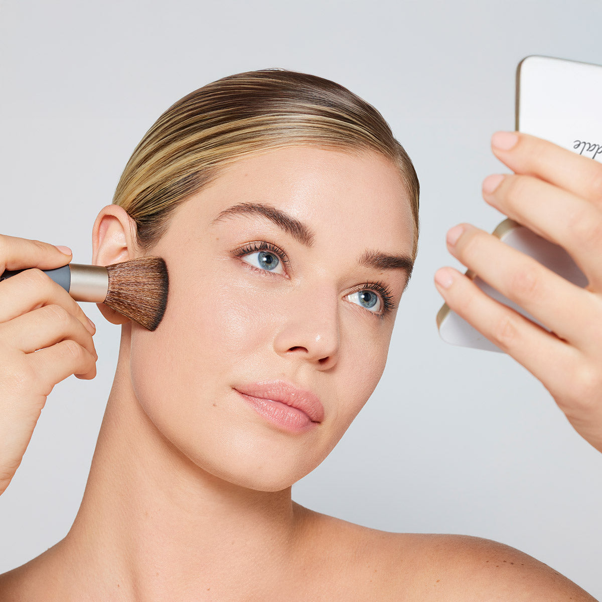 Care Concept Onlineshop - jane iredale - Ein Model trägt sich mit dem Handi Brush das Pure Pressed Base Mineral Puder im Gesicht auf